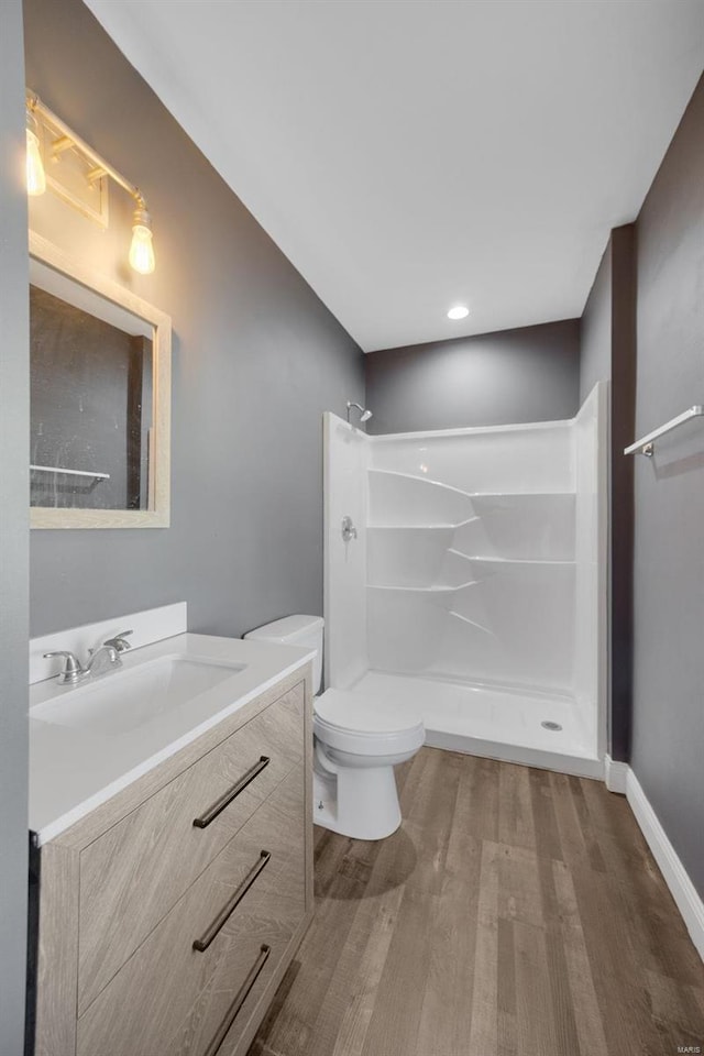 full bathroom featuring baseboards, toilet, wood finished floors, vanity, and a shower stall