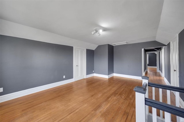 empty room featuring baseboards, vaulted ceiling, and wood finished floors