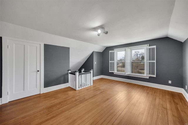 additional living space with lofted ceiling, wood-type flooring, and baseboards