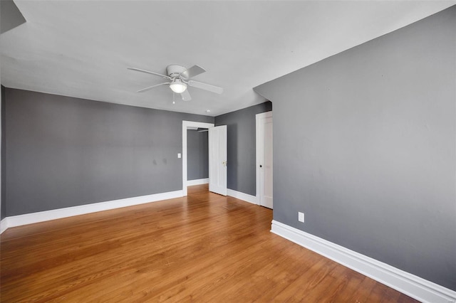 empty room featuring ceiling fan, light wood-type flooring, and baseboards