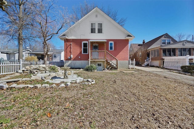 view of front of property with a sunroom, fence, and brick siding