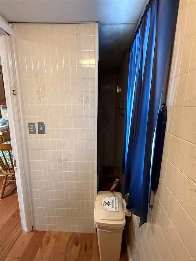 bathroom with tile walls, toilet, and wood finished floors