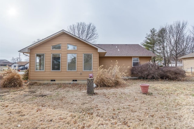 rear view of house with a shingled roof and crawl space