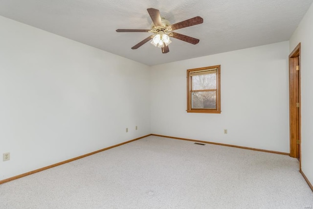 empty room featuring visible vents, light carpet, a textured ceiling, and baseboards