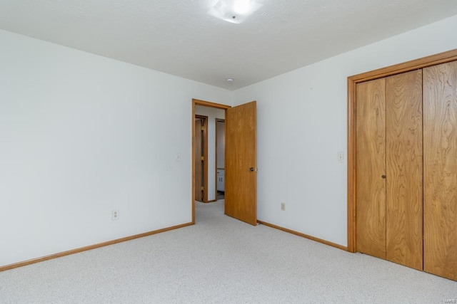 unfurnished bedroom featuring a closet, carpet flooring, a textured ceiling, and baseboards