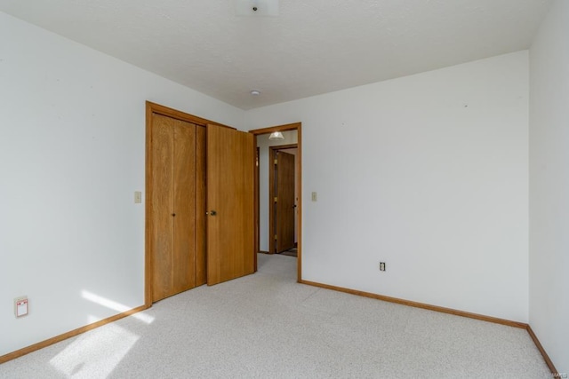 unfurnished bedroom with light carpet, a closet, and baseboards