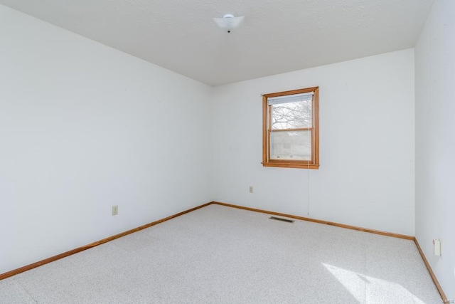 carpeted spare room featuring baseboards and visible vents