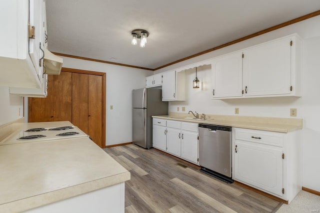 kitchen featuring white cabinets, appliances with stainless steel finishes, ornamental molding, light countertops, and a sink