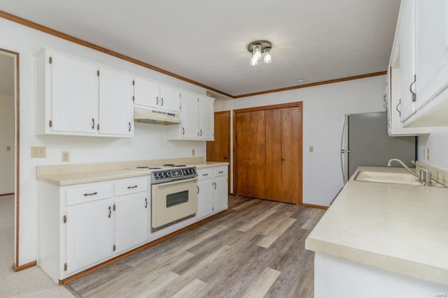 kitchen with under cabinet range hood, a sink, white cabinets, electric stove, and crown molding