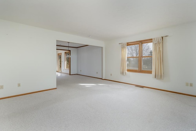 carpeted spare room featuring visible vents and baseboards