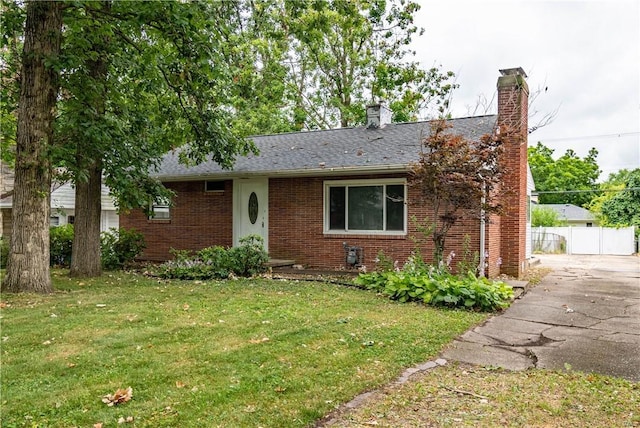 ranch-style home featuring brick siding, a shingled roof, fence, a front lawn, and a chimney