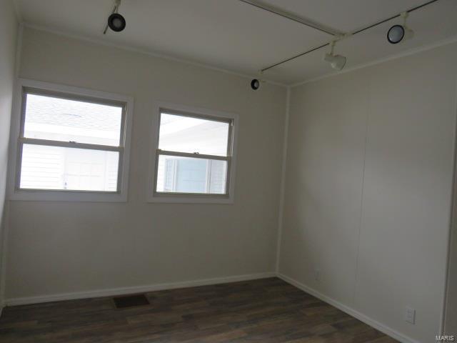 unfurnished room featuring dark wood-style floors, visible vents, baseboards, and track lighting