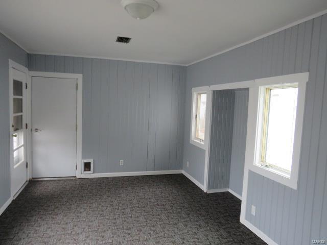 empty room with dark colored carpet, visible vents, and baseboards