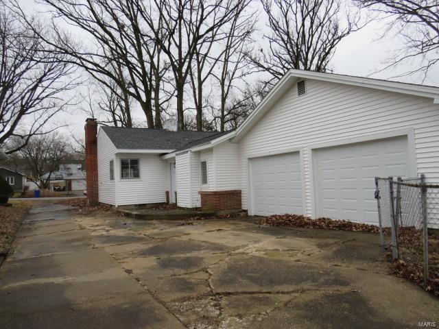 single story home with an attached garage, a chimney, and concrete driveway