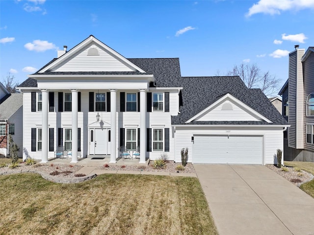 greek revival house with a front yard, an attached garage, roof with shingles, and driveway