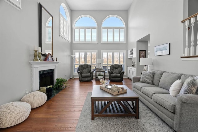 living area featuring a premium fireplace, wood-type flooring, and a towering ceiling