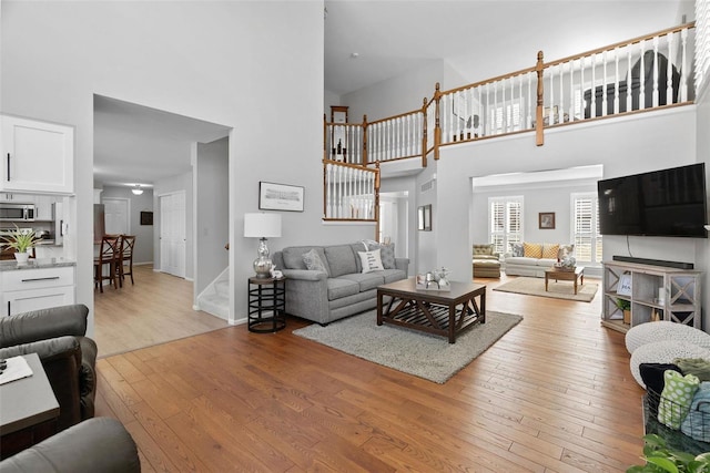 living room featuring light wood finished floors and a towering ceiling