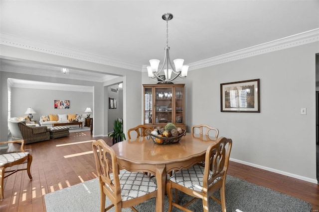 dining space featuring baseboards, wood-type flooring, an inviting chandelier, and crown molding