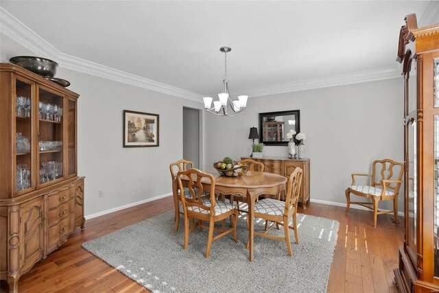 dining space featuring baseboards, an inviting chandelier, wood finished floors, and crown molding