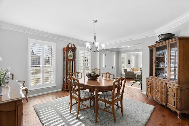 dining room with baseboards, crown molding, an inviting chandelier, and hardwood / wood-style flooring