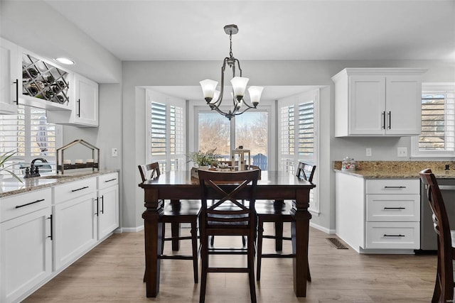 dining area with a chandelier, visible vents, a healthy amount of sunlight, and light wood-type flooring