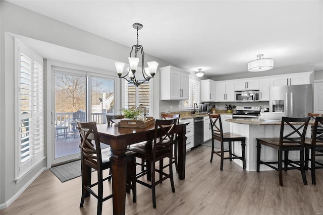 dining space with an inviting chandelier, baseboards, and light wood-style floors