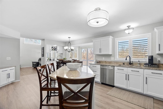 kitchen with stainless steel dishwasher, light wood finished floors, white cabinetry, and a sink