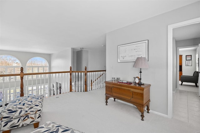 hall featuring baseboards, carpet, and an upstairs landing