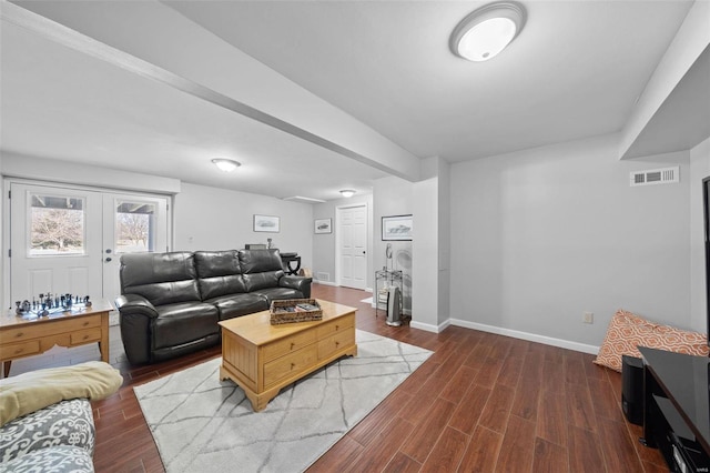 living room with dark wood finished floors, visible vents, and baseboards