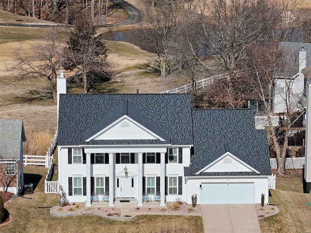 view of front of home with an attached garage, a chimney, driveway, and roof with shingles