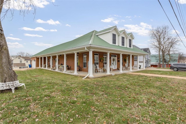 view of front of property featuring metal roof, brick siding, a porch, and a front yard