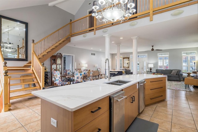 kitchen featuring open floor plan, light tile patterned floors, a sink, and decorative columns