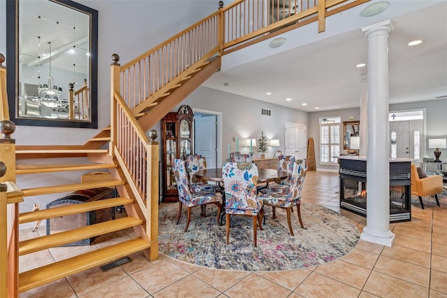 dining area featuring visible vents, stairway, tile patterned flooring, a high ceiling, and ornate columns