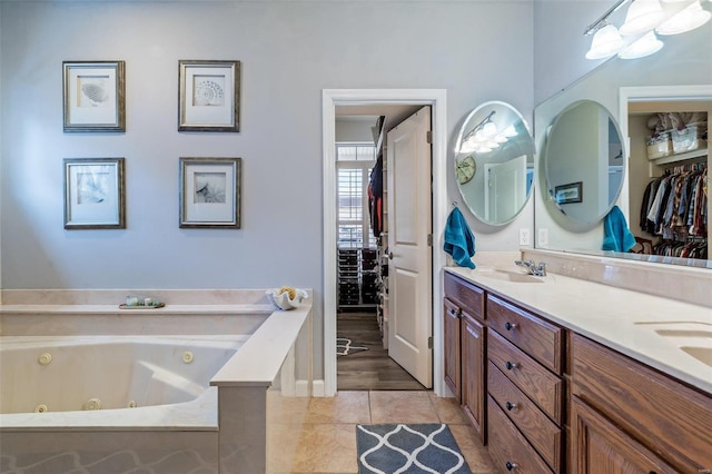 bathroom featuring double vanity, a jetted tub, a sink, and tile patterned floors