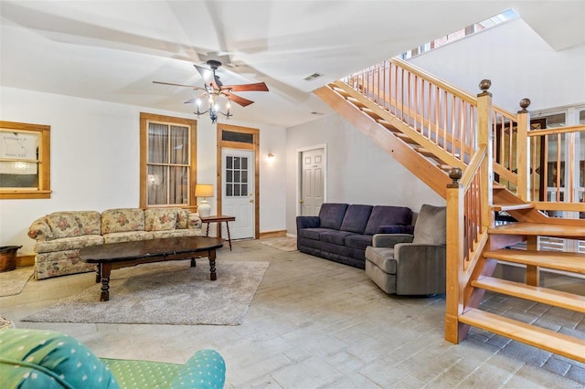 living room featuring stairs, baseboards, visible vents, and a ceiling fan