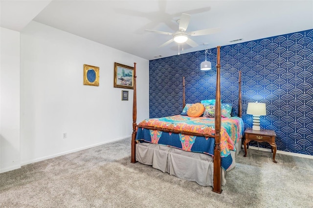 carpeted bedroom featuring an accent wall, a ceiling fan, baseboards, visible vents, and wallpapered walls