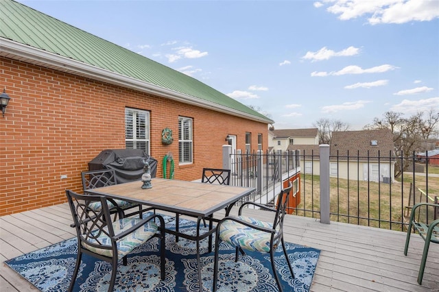 wooden terrace with a grill, fence, and outdoor dining space