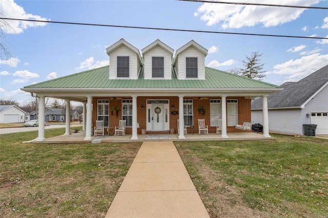 view of front of property featuring covered porch, metal roof, a front lawn, and brick siding