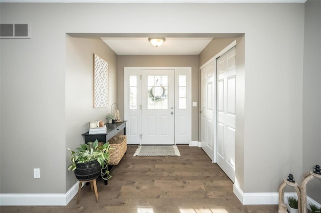 entryway with baseboards, visible vents, and wood finished floors