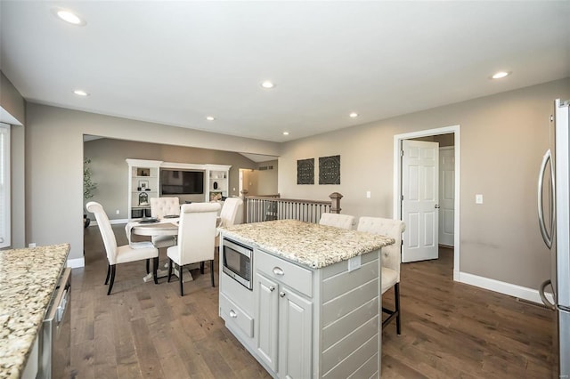 kitchen featuring a kitchen bar, appliances with stainless steel finishes, dark wood-style flooring, and recessed lighting