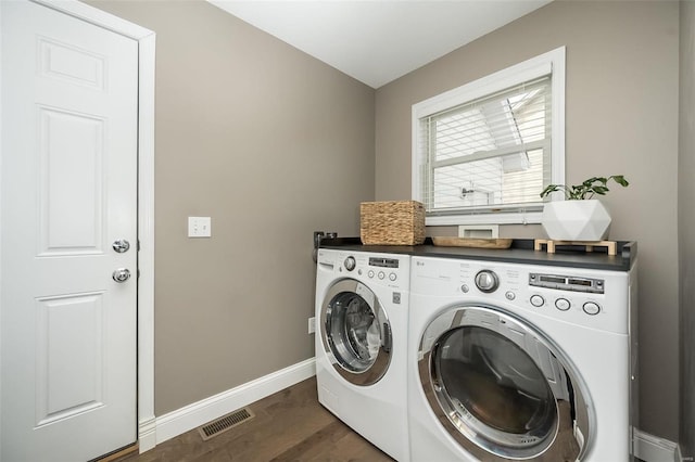 laundry room featuring laundry area, visible vents, baseboards, dark wood-style floors, and washing machine and clothes dryer