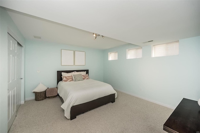 bedroom with a closet, light carpet, visible vents, and baseboards