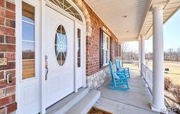 view of exterior entry featuring brick siding and a porch