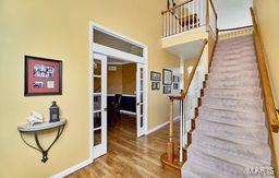 stairs featuring a towering ceiling, french doors, baseboards, and wood finished floors