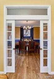 dining area featuring french doors, an inviting chandelier, and wood finished floors