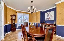 dining area featuring a wainscoted wall, wood finished floors, an inviting chandelier, and ornamental molding