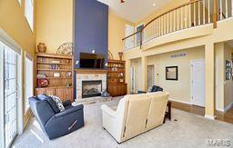 living room featuring a high ceiling and a fireplace with raised hearth