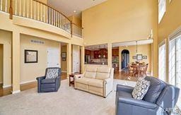 carpeted living area with baseboards, plenty of natural light, and a towering ceiling