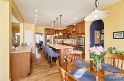 dining space featuring light wood finished floors, recessed lighting, and arched walkways