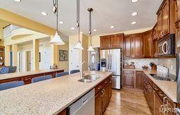 kitchen with tasteful backsplash, decorative light fixtures, light wood-type flooring, appliances with stainless steel finishes, and a sink